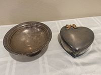 Silver candy dish and heart-shaped ring box side by side on tablecloth