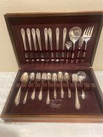 Open wooden flatware box showing upper section with forks and large serving utensils.