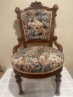 Front view of Victorian upholstered side chair showing floral upholstery and carved wooden frame.