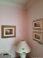 Photo showing three framed signed canvas art paintings on wall with tags indicating sizes.