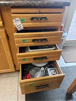 Four wooden drawers filled with assorted kitchen items such as utensils, bakeware, and tools.