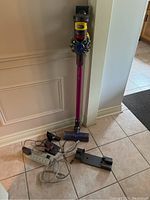 Full view of stick vacuum with extension wand, motorized floor head, charger and docking station on tile floor