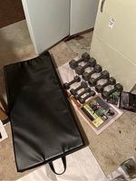 Wide angle photo showing black workout mat, multiple dumbbells, digital pedometer, and walking guide booklet on the floor.
