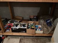 Shelf with various boxes containing light bulbs, lighting fixtures, shower supplies, and plumbing parts.