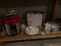 Wolfgang Puck pressure cooker, Ampery white dish set with plates and bowl, Angry dish set cups and saucers on wooden shelf