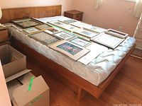 Overall view of teak double bed frame with mattress and picture frames (not included) showing headboard and side rails