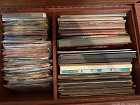 Top-down photo showing two compartments filled with numerous vinyl records mainly in paper sleeves, some titles visible on spines.