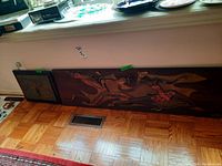 Both wood panels leaning against wall on parquet floor, one large and one small