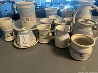 Overview photo showing all 15 pottery pieces including tray, jugs, mugs, teapot, butter dish, flower vase, and wax melt warmer, all with hand-painted nature scenes.