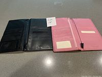 Photo showing inside of black and pink leather passport covers displaying card slots and compartments