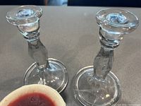 Two tall clear crystal candle holders with faceted stems on flat round bases