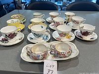 Photo showing all 12 tea cups and saucers arranged with creamer, sugar bowl, and tray