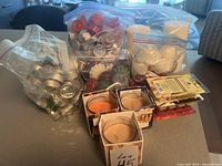 Overview of bags with silver tea lights, floating candles, assorted votive candles in boxes, and pillar candles on table.