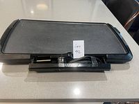 Electric Presto griddle viewed from the front showing the grease tray and control unit inserted.