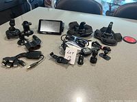 Overview of Garmin GPS unit with dashboard holders, cell phone holders, chargers, and cables laid out on table.