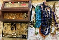 Overview of jewelry including three wooden boxes with glass tops containing faux pearl necklaces and earrings, and a group of colorful wood bead necklaces