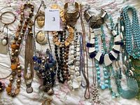 Overview of mixed costume jewelry including necklaces and bracelets featuring beads, metal pieces, and pendants in various colors and styles.