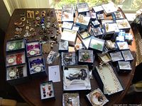 Overview of large assortment of costume jewelry including boxed Strada watches and loose earrings, brooches, necklaces.