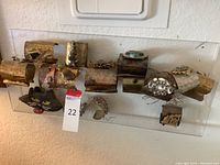 Clear acrylic board holding multiple handmade metal cuff bracelets and beaded cat face purse