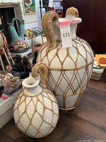 Two large ceramic pots wrapped in rattan, the larger with two handles and the smaller with one.