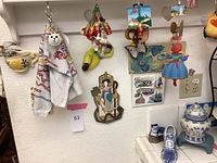 Wall display with various hanging and wall mounted colorful decor items including figurines of clown, butterfly on floral board, and other small hanging pieces.