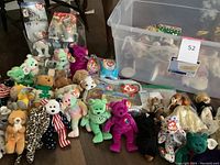 Photo of multiple Beanie Babies in various styles and colors, arranged on the floor next to a large plastic tub with vintage dolls inside.