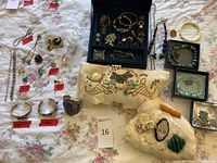 Full view of jewelry lot and two embroidered pillows showing a mix of earrings, rings, bracelets, and brooches.