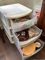 Plastic storage container with three drawers opened showing contents of various jewelry supplies and tools.