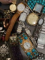 Close-up of various women's watches with different designs and materials including leather strap, metal bands, and turquoise inlaid bracelet watch.