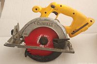 Side view of DeWalt circular saw showing yellow handle, red blade, and metal blade guard with wear and usage marks.