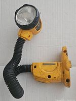 Yellow DeWalt cordless work light with flexible neck and visible wear and dirt.