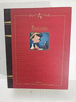 Box cover showing a red and black design with an image of Pinocchio and gold detailing with text 'Pinocchio' and Disney branding.