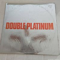 Front cover of Kiss Double Platinum vinyl album showing embossed silver background with red lettering
