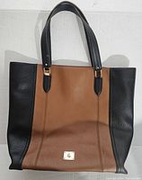 Front view of two-tone Lauren by Ralph Lauren purse bag, showing black sides and handles with brown center panel and gold hardware.