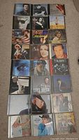 24 country music CDs arranged in four rows on carpet showing album covers of various artists