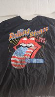 Front of black Rolling Stones 2019 No Filter Tour T-shirt showing tongue logo with American flag tongue and 'Rolling Stones' and 'Tour 2019' text.