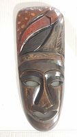 Front view of wood mask showing entire face and decorative upper design
