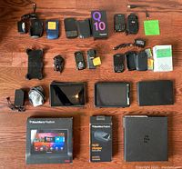 Overall lot content showing phones, tablets, accessories, boxes, and cases arranged on wooden floor