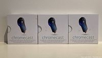 Front view of three original white Chromecast boxes, each showing the image of the Chromecast device.
