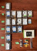 Top view showing front labels of 15 hard drives with capacity identification tags and USB drives next to boxed CoolMax converter.