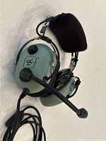 Headset front view showing green ear cups, boom mic and cable with dual plugs