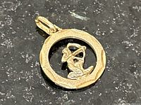 Front view of gold pendant featuring an archer in a textured circular frame, showing detailed craftsmanship.