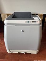 Front view of HP Color LaserJet 2600n printer showing control panel and paper output tray.