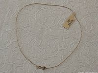 Full view of delicate 10K gold chain necklace laid out flat showing overall condition and attached paper tag.