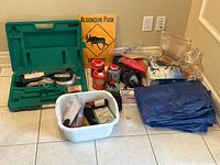 Full overview of the camping lot including tools, propane tanks, tarps, sign, and accessories.