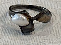 Close-up front view of the vintage modernist sterling silver ring with white pearl, showing asymmetrical design and pearl shape.