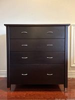 Front view of the dark wood chest showing all four drawers and metal handles.