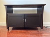 Front view showing dark wood console table with open shelf and double-door cabinet with silver handles and metal-accents on legs.