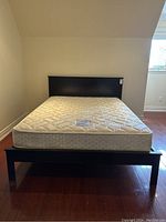 Front view of the dark wood bed frame with headboard and optional mattress visible on top.