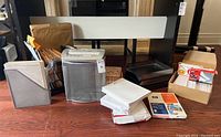 Full view of office lot showing paper shredder, file holders with papers, white binders, index cards, and additional office supplies on wooden floor.